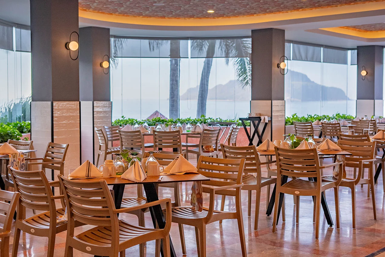 Restaurante El Mirador con vista panorámica al mar, mesas preparadas y ventanales frente a la costa de Mazatlán.