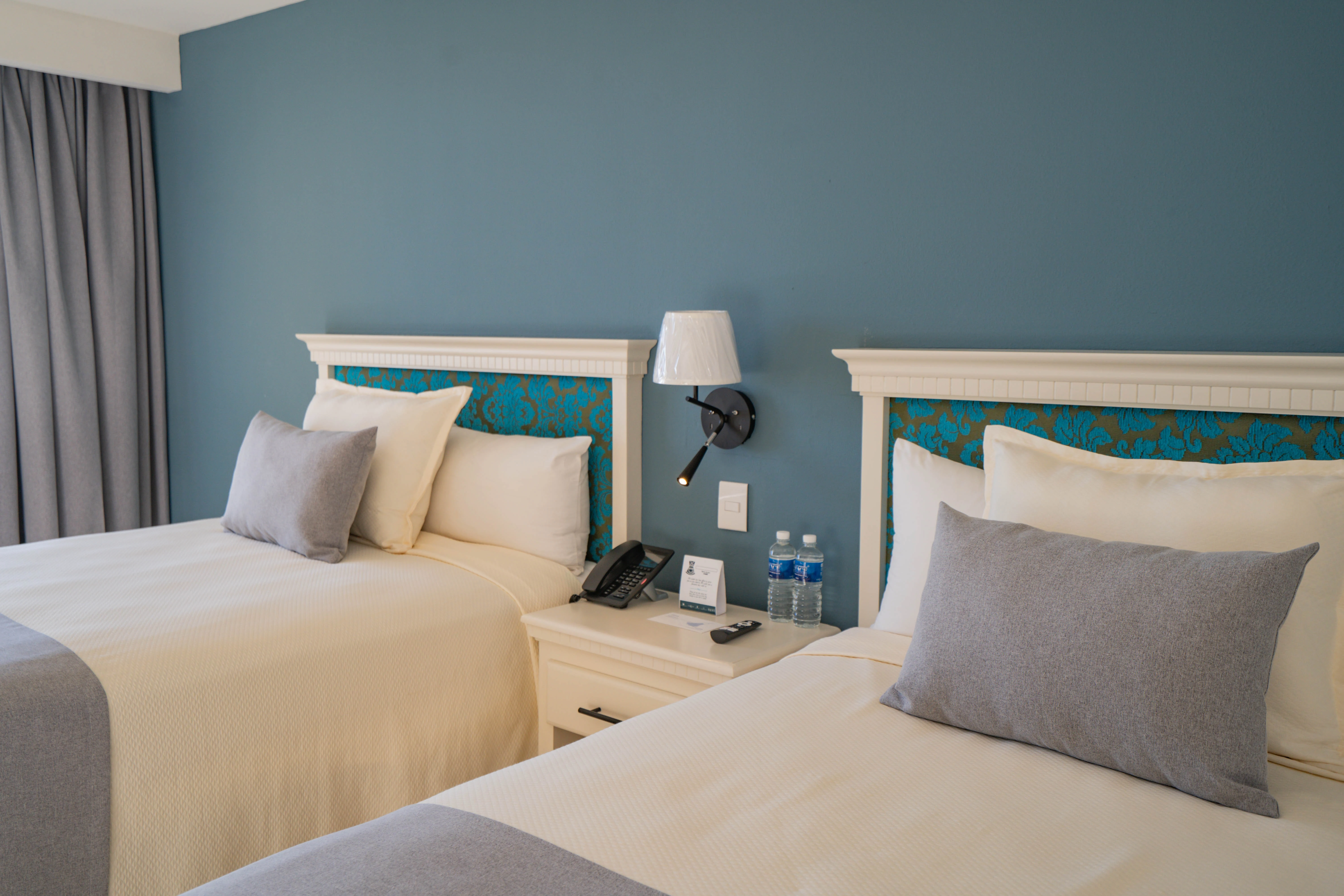 Habitación standard, camas dobles individuales con vista a la ciudad, buro y amenidades de hotel sunset palace Mazatlán